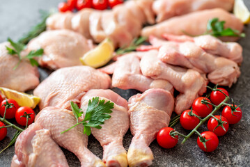 Set of raw chicken fillet, thigh, wings, strips and legs on a stone background of a culinary table with spices