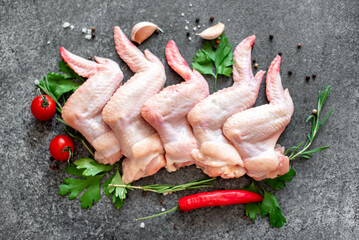 raw chicken wings with spices on stone background