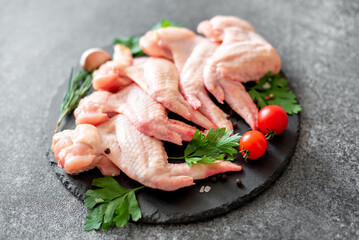 raw chicken wings with spices on stone background