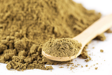 Hemp protein powder in a wooden spoon on a white background.