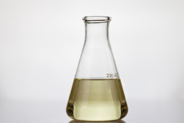 yellow oil on scientific glassware on white background. example lubricant oil for testing.