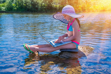 Young child girl having a video chat through laptop. Summer vacation and holiday concept, studying online with tablet, distance learning, self education, beach work