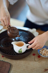 Fototapeta na wymiar close up of hands pouring tea from teapot to teacup in a traditional asian tea chamber