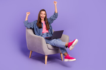 Full body portrait of overjoyed satisfied person sit chair raise fists celebrate triumph isolated on purple color background