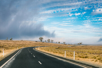 open empty road surrounded by farms and fields in Australia. Road trip travel