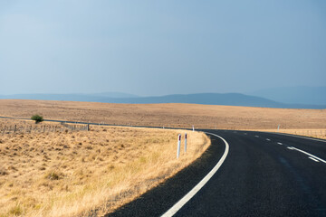 Winding open empty road surrounded by farms and fields in Australia. Road trip travel