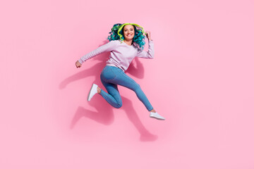 Full length portrait of excited delighted girl raise fists jumping toothy smile isolated on pink color background