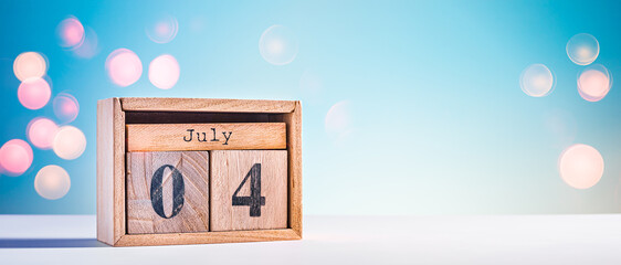 Cute wooden calendar with fourth of July date on blue sky background. Background for US...