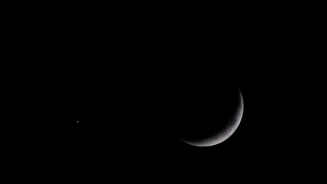 Scene of a waxing crescent moon shining alongside a single bright star against a dark black sky, enhanced by a subtle heat haze effect. Composition copy space,  ideal for various creative uses.