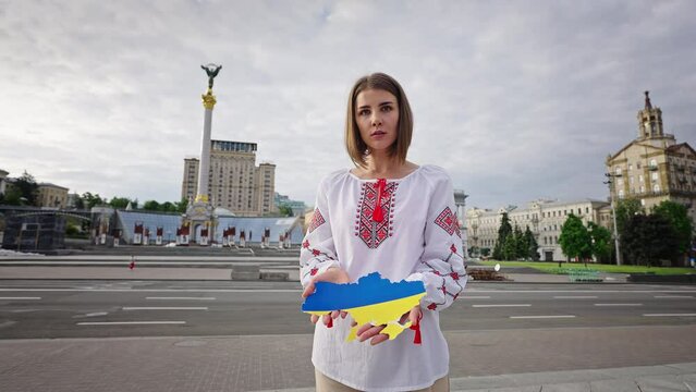 Woman holds cut paper map of Ukraine painted in flag colors
