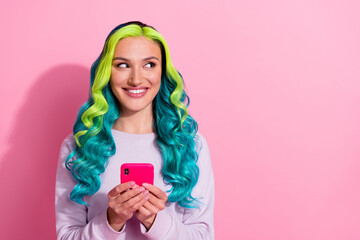 Portrait of pretty cheerful girl look interested empty space hold telephone isolated on pink color background