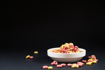 Corn rings of quick breakfast powder on a plate on a black background with place for text
