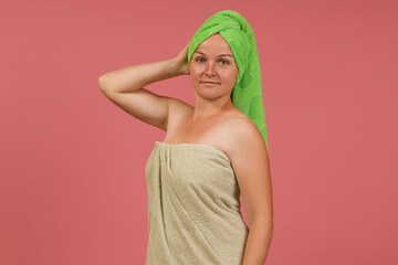 a clean woman after a shower tied a towel on her head on a colored background