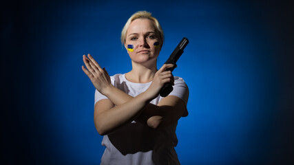 a woman with a gun and a Ukrainian flag on her face, crossed her arms in a stop sign on a dark background