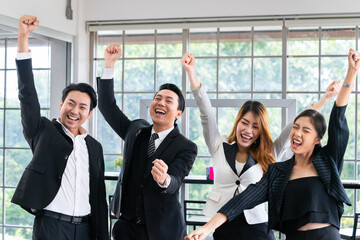 A group of young businessmen in suits, Asians, are determined and excited about their work. and encourage the team members by raising their hands happily