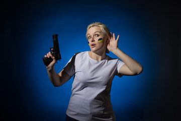 A woman with a gun and a blue and yellow Ukrainian flag on her cheek eavesdrops. Dark background.