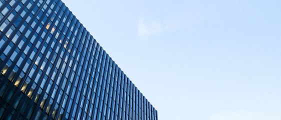 Modern high-rise building against the blue sky. Bottom view of a skyscraper in the business...