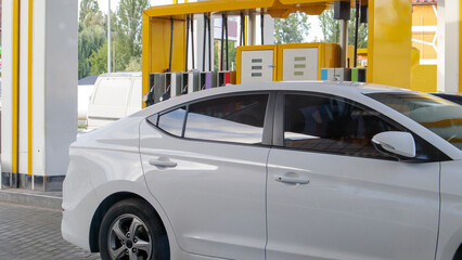 The white car is refueling. Refueling a car parked at a gas station. Refuel cars with petrol pump...