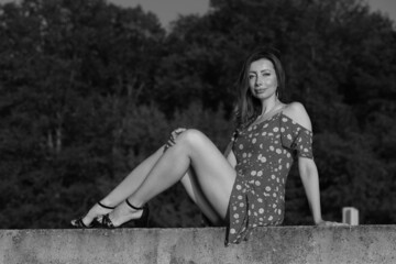 Beautiful woman sitting on a concrete fence in black and white