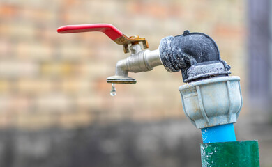 Water faucet on the background of nature. Opening or closing a faucet to save water indicates a...