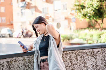 Fototapeta premium Happy woman using a smart phone in the street with an unfocused background