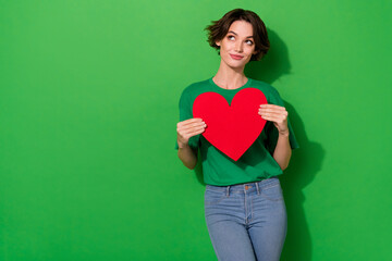 Portrait of minded pretty lady hold big heart postcard look empty space isolated on green color background