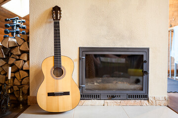 Yellow acoustic guitar standing leaning wall of build-in mantelpiece in domestic room