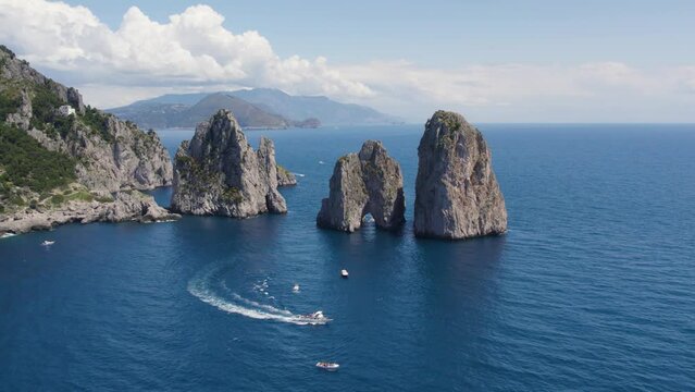 Tourists Boating by the Epic Faraglioni Rocks off Capri Island, Italy - Aerial