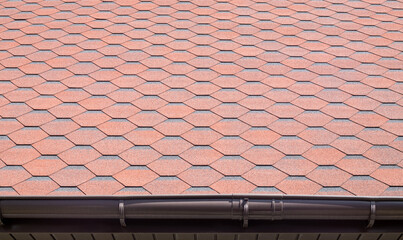 New roof with red shingles. Tiles on the roof of the house. Use to advertise roof fabrication and maintenance. Spotted texture. Affordable roofing. High quality photo with copy space.