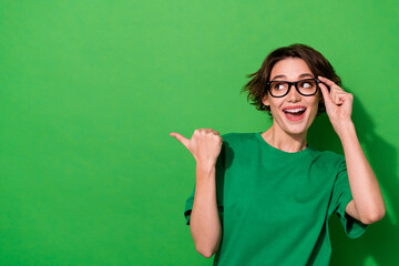 Photo of adorable funny woman wear casual t-shirt eyeglasses pointing thumb looking empty space...