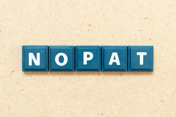 Tile alphabet letter in word NOPAT (Abbreviation of net operating profit after tax) on wood background