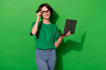 Photo of clever cute woman wear casual t-shirt arm spectacles chatting modern device isolated green color background