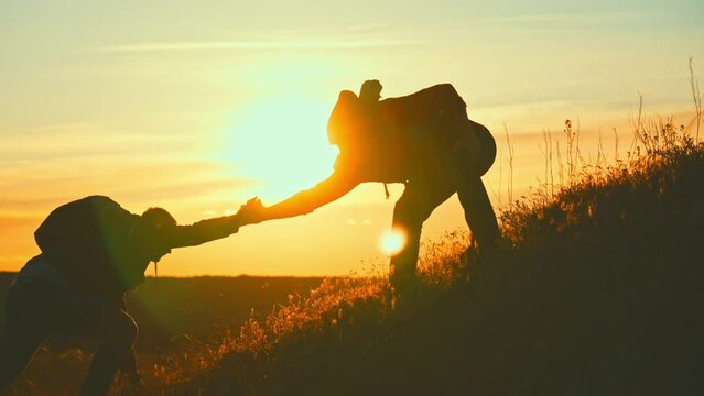 Silhouette two people working in team mountain rock climbing. Helping hand friend to overcome difficulties. Dangerous sport in nature. Business partner. Tourists with backpack and hiking accessories.