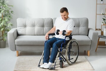 sportsman sitting in wheelchair and outstretching arms with dumbbells during rehabilitation exercise in modern medical center. Man sitting on wheelchair at home