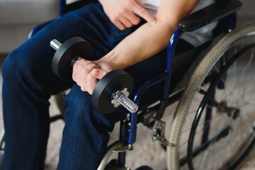 Naklejka na ściany i meble Man Disabled. Sports for Disabled. Male in Wheelchair with Dumbbells in Hands. Man with Dumbbells in Hands. Father Disabled Do Spotting. Sport at Apartment. Health Concept. Healthy Lifestyle
