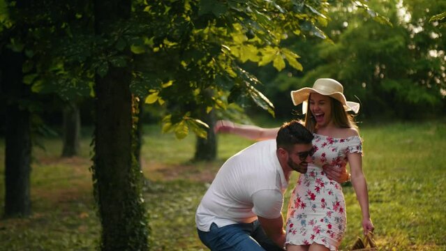 Guy carrying a girl in his arms as they look at each other romantically walking in the forest