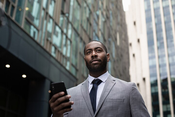 Businessman walking in city using smartphone on his commute