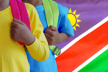 Two children with satchels background of Namibia flag. The concept of raising and educating children in Namibia