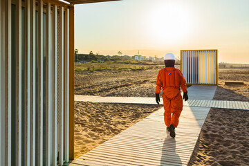 Anonymous astronaut walking on beach at sunset