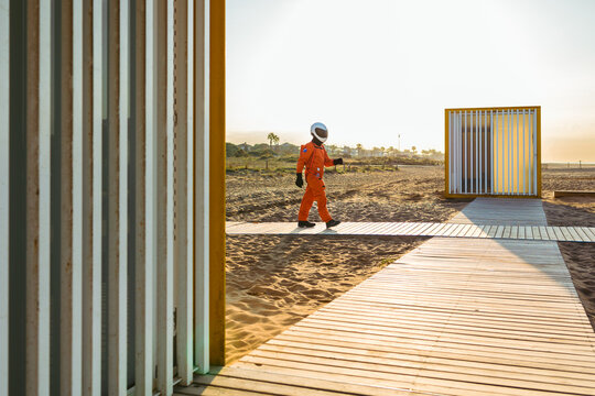 Anonymous astronaut walking on beach at sunset