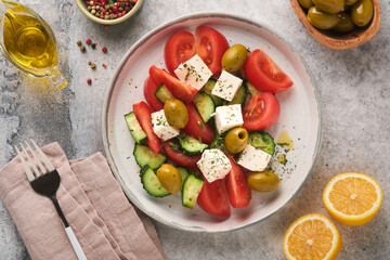 Greek salad. Fresh Greek salad with fresh vegetables, tomato, cucumber, green olives and feta cheese on old grey concrete table background. Top view.