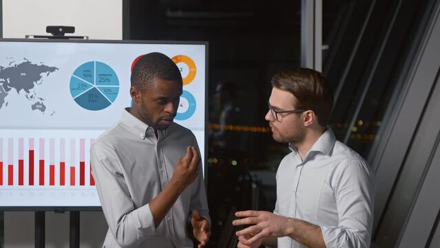 Two men chatting on the background of multimedia after a presentation