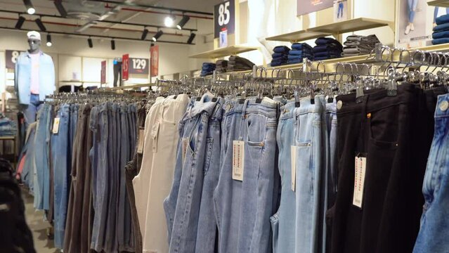 BATUMI, GEORGIA - May 26, 2022:Jeans or Denim pants hanging on rack in clothes shop. Fashion product collection in clothing store for selling. Textile industry and business concept