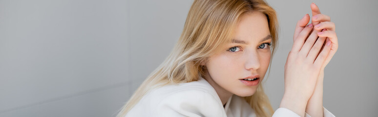 Fototapeta premium Woman in white jacket looking at camera at home, banner.