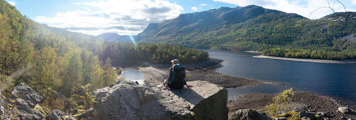 Female backpacker in Stavanger Norway with sun burst and summer fjord background