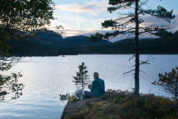 Obraz premium Male Hiker and dog camping in the Fjords of Stavanger Norway with sunset and summer background