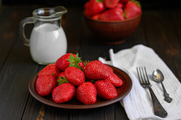 A bowl of red juicy strawberries on rustic wooden table. Healthy and diet snack food concept.