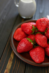A bowl of red juicy strawberries on rustic wooden table. Healthy and diet snack food concept.