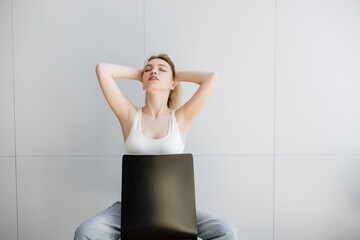 Pretty woman with closed eyes touching hair while sitting on chair at home.