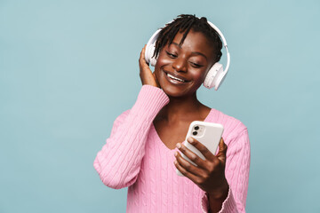 African american woman smiling while using cellphone and headphones